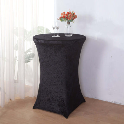 Black stretch table cover on a tall round table with a floral centerpiece.
