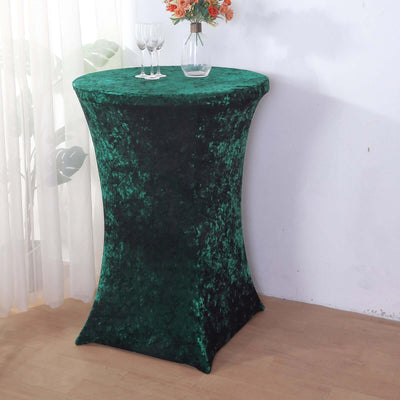 Green velvet table cover on a cocktail table with glasses and flowers.