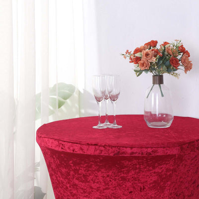 Red velvet table cover with glasses and a flower vase.