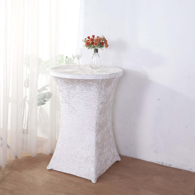 Round white table with a textured cover and floral arrangement on top.