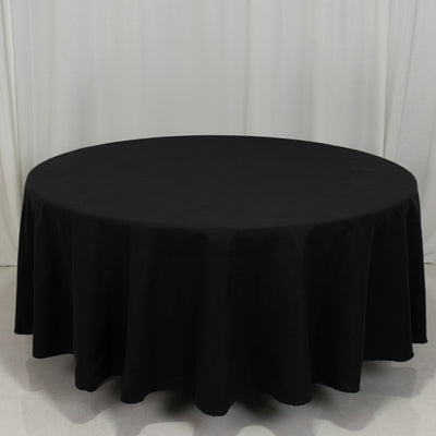 Black round tablecloth on a plain backdrop.