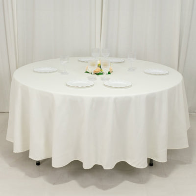 Round white table set for dining with plates and glasses.