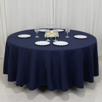 Round navy tablecloth draped over a table with white plates and glassware.