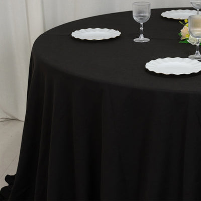 Black tablecloth draped over a table set with white plates and glassware.