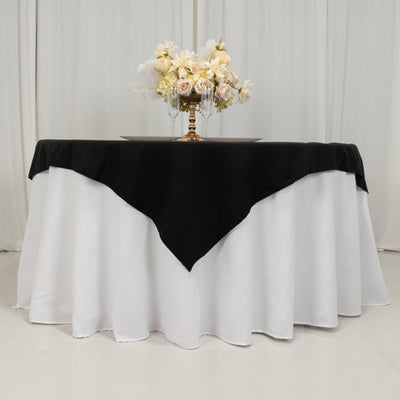 Elegant table setting with black and white tablecloth and floral centerpiece.