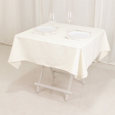 White tablecloth draped over a folding table set for two with plates and glasses.