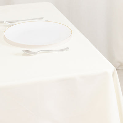 White dinner plate with gold rim on a cream tablecloth.