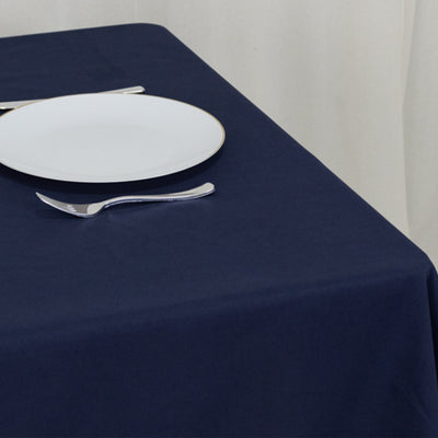 Navy tablecloth with a white plate and utensils set on a dining table.