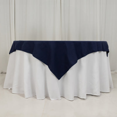 Navy tablecloth draped over a round white table in a studio setting.