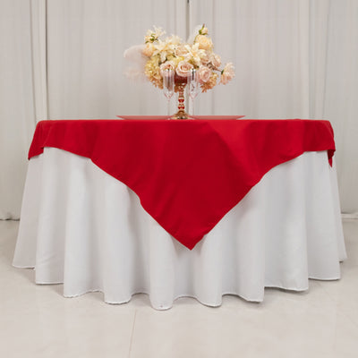 Red tablecloth draped over a white table with floral centerpiece.