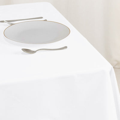 Elegant white plate with gold rim on a white tablecloth