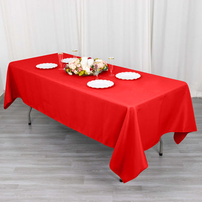 Red tablecloth draped over a table with decorative plates and flowers.