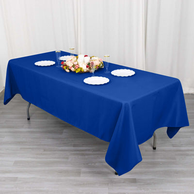 Blue tablecloth on a dining table with decorative flowers and plates.