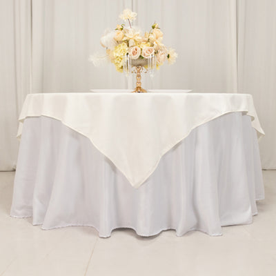 Elegant white tablecloth draping over a round table with floral centerpiece.