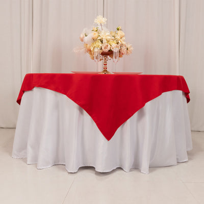 Red tablecloth on a white table with floral centerpiece arrangement.