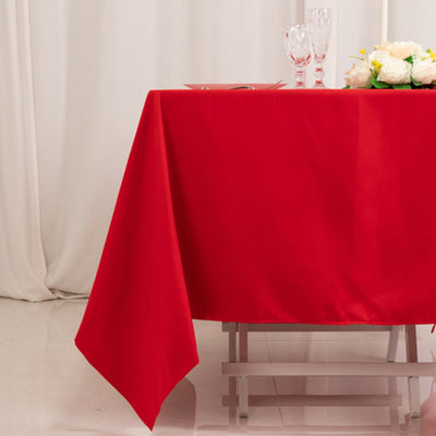 Red tablecloth draped over a table with floral centerpiece and glassware.