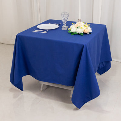 Blue tablecloth on a dining table set with plates and a floral centerpiece.