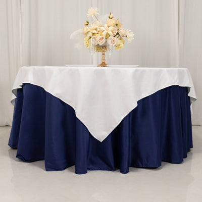 Elegant navy tablecloth with white overlay, styled with floral centerpiece.