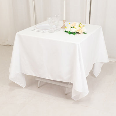 Elegant white table setup with flowers and dinnerware.