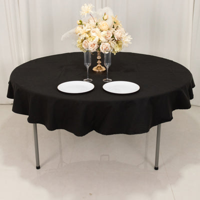 Round black tablecloth with plates and floral centerpiece.