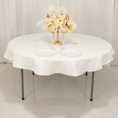 Round table set with a floral arrangement and plates on a white tablecloth.