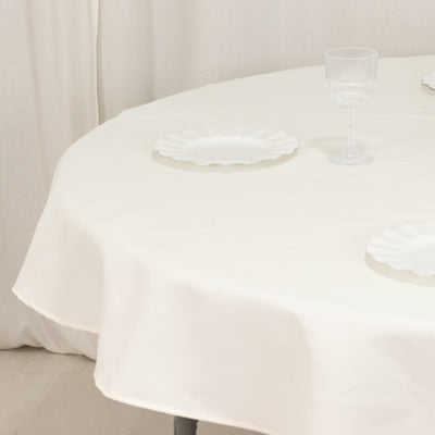 Round table with a white tablecloth and empty decorative plates.