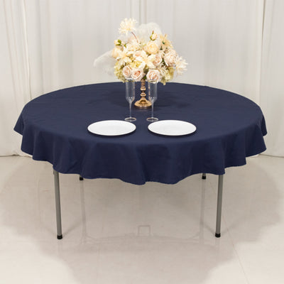 Round navy tablecloth draped over a table with plates and floral centerpiece.