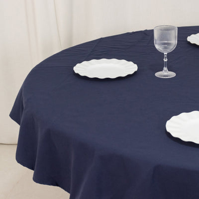 Navy tablecloth with white plates and glass on a round table.