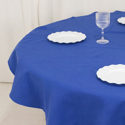 Blue round tablecloth with white plates and glass on a plain background.