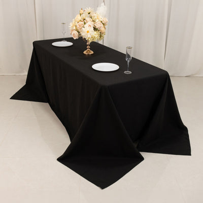 Elegant black tablecloth draped over a table set for dining with floral centerpiece.