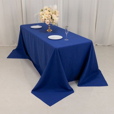 Blue tablecloth draped over a table with floral centerpiece and plates.