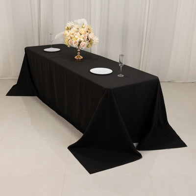 Elegant black tablecloth with floral centerpiece and table settings.