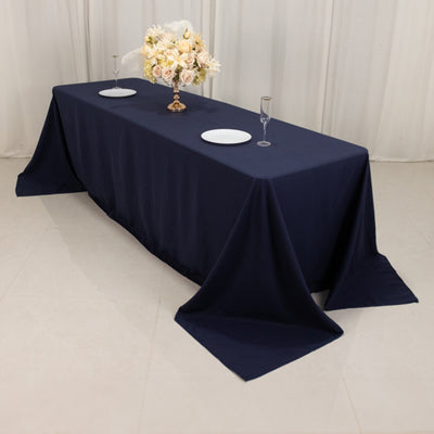 Navy tablecloth draped over a long table with plates and floral centerpiece.
