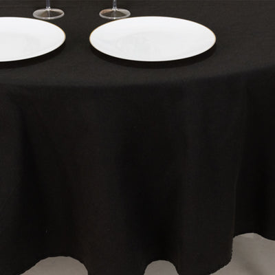 Black tablecloth draping over a table with white plates on top.