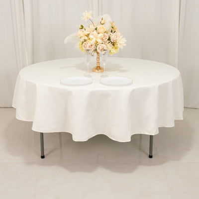 Round table with a white tablecloth and floral centerpiece.