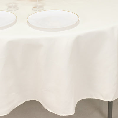 Elegant white tablecloth draping over a table with plates and wine glasses.