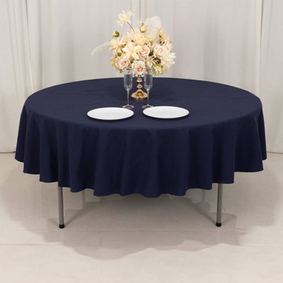 Round navy tablecloth with elegant floral centerpiece and plates set for dining.