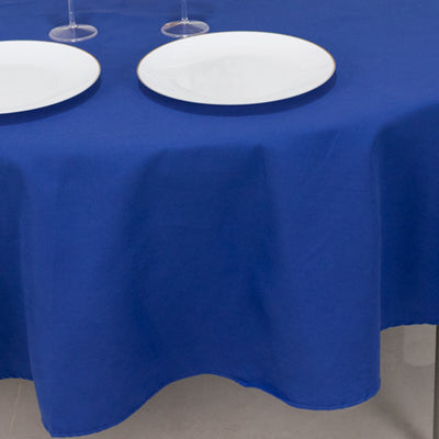 Blue tablecloth draping over table with white plates and glasses.