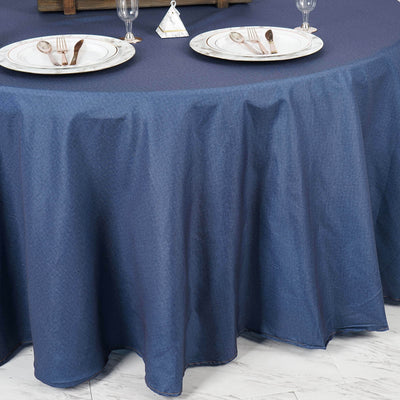 Round navy tablecloth draping over a table set for dining.