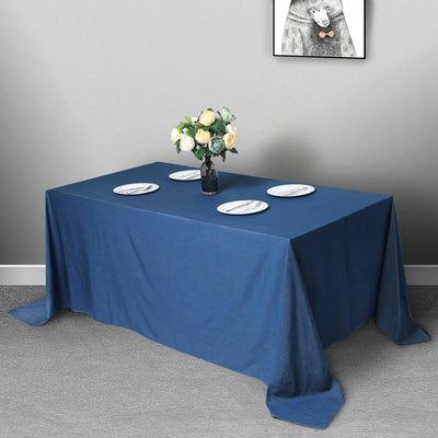 Blue tablecloth draped over a table with plates and a vase of flowers.