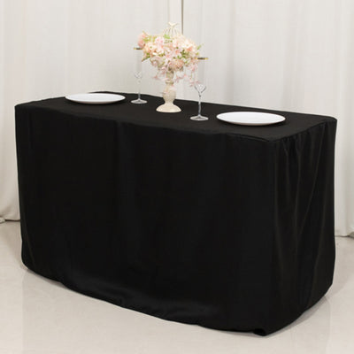 Black tablecloth draped over a table set for dining with plates and floral centerpiece.