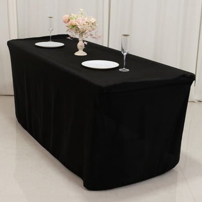 Black tablecloth draped over a table set for dining with plates and glasses.