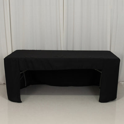 Black table cover on a folding table against a plain backdrop.