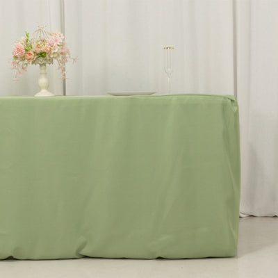 Green tablecloth draping a table, styled with floral arrangement and glassware.