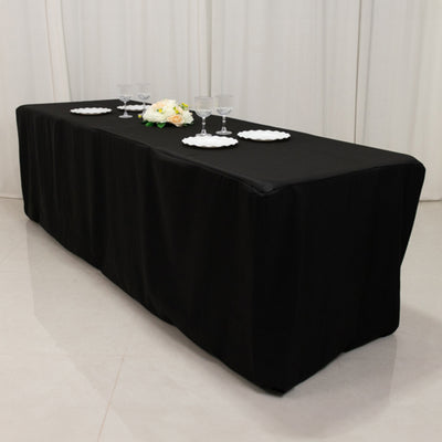 Black tablecloth draped over a table with plates and glasses on top.