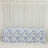 Floral patterned tablecloth draped over a table against white curtains.