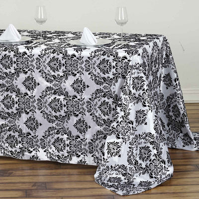 Elegant black and white damask tablecloth draped on a wooden table.