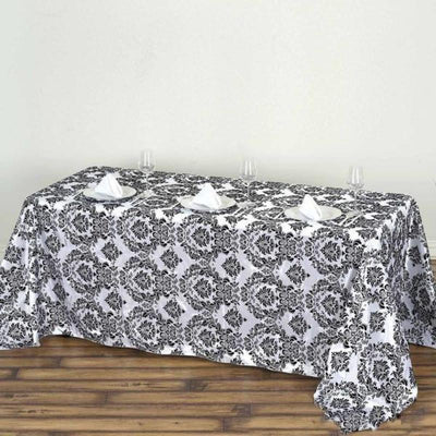 Elegant black and white damask tablecloth on a wooden table.