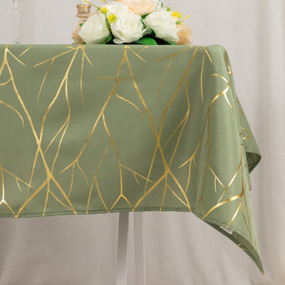 Green tablecloth with gold branches design, styled with floral centerpiece.