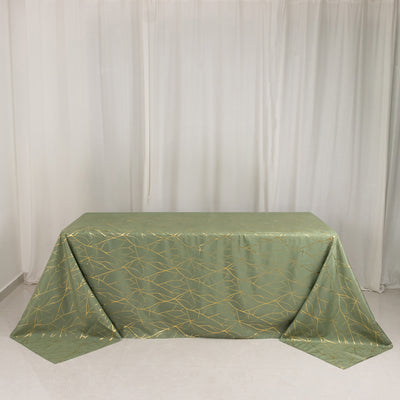 Green tablecloth with gold geometric design on plain backdrop.